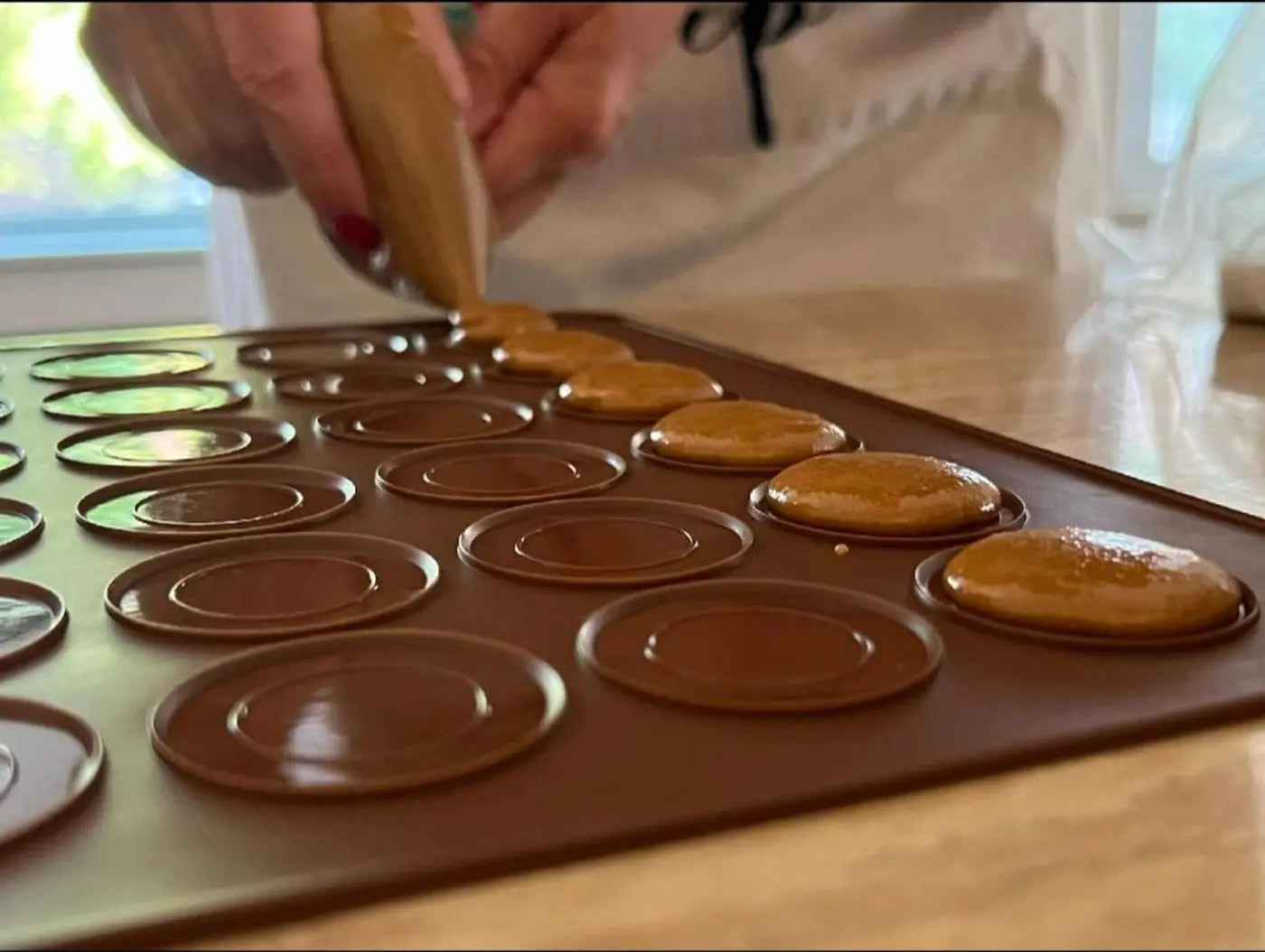 Macaron batter being piped by hand