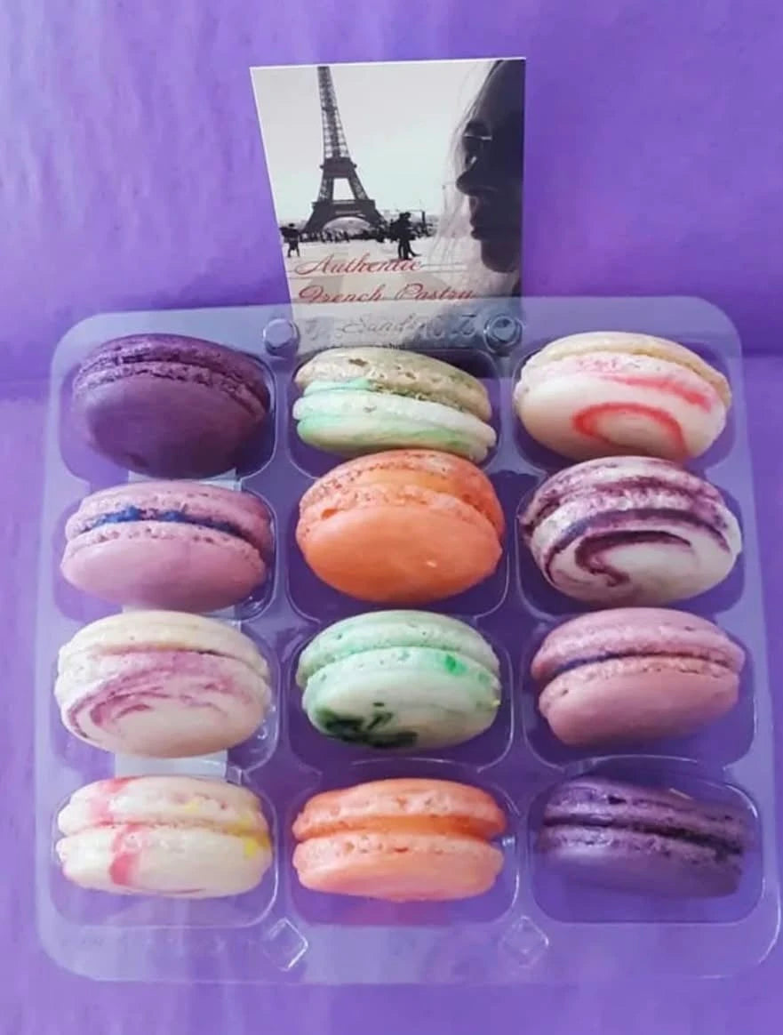 Macarons arranged in a transparent protective tray inside their shipping box